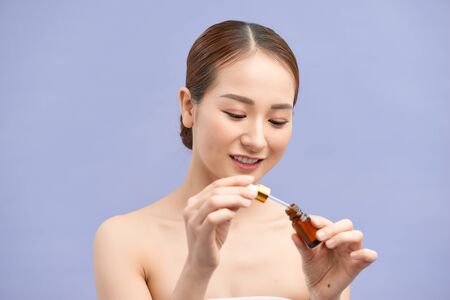 girl applying eye serum isolated on violetの写真素材