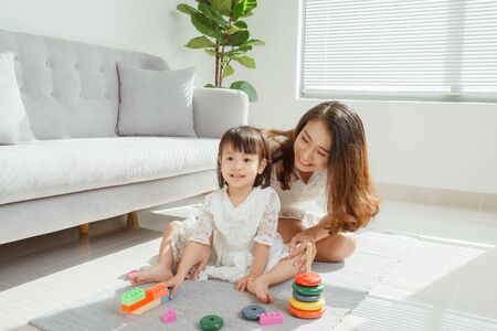 Asian mother and daughter playing toy in house