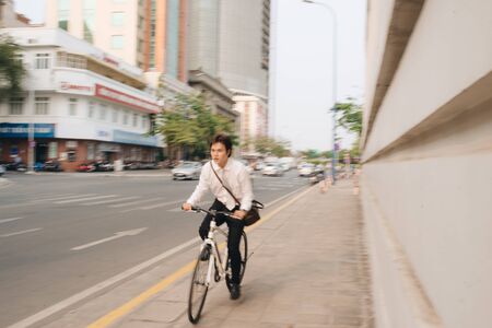 Blur concept. Hurry Asian businessman riding bike in rush hour.  Young man late for train work,...