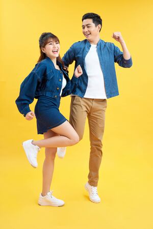Full length body size photo funky she her he him his pair jumping high raised fists yell scream shout loud wear casual jeans denim white t-shirts isolated yellow backgroundの写真素材