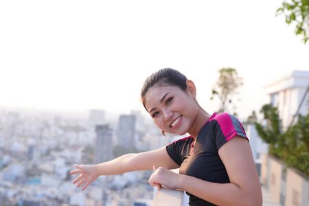 Portrait of young sporty Asian woman enjoying top view of building.の写真素材