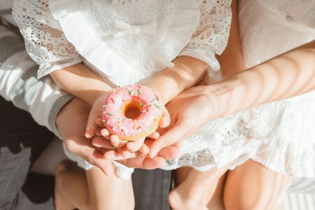 Happy mom and her daughter holding donut cakeの写真素材