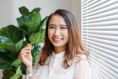 Beautiful asian women healthy diet eating vitamin pill with waterの写真素材