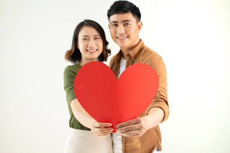 Happy young Asian couple holding heart shape over white background.の写真素材