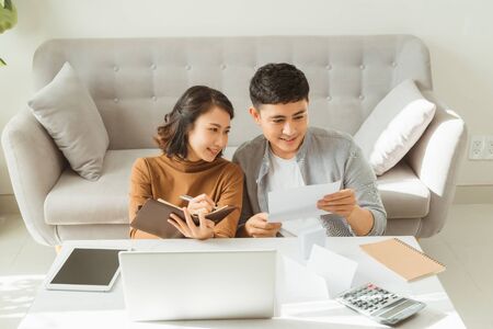 Happy couple with laptop spending time together at homeの写真素材