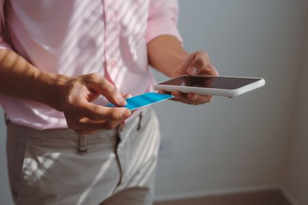Man holding mobile phone with Payment Detail page display and credit card, online shopping concepts