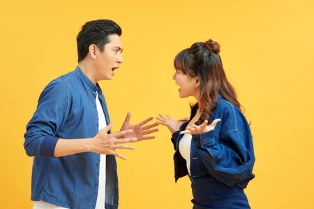 Profile side view portrait of two attractive angry aggressive nervous people having fight anger blame isolated over vivid shine bright orange background. Negative emotions concept.の写真素材