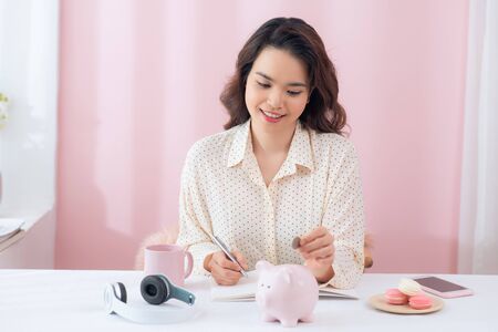 Woman putting coin in piggy bank. saving money, budget, investment, finance conceptの写真素材