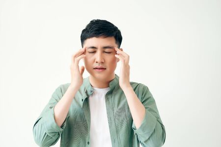 healthcare, pain, stress, age and people concept - Young asian man suffering from headache on white backgroundの写真素材