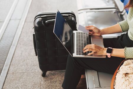 Young woman using credit card to pay online by her laptop at the airport.の写真素材