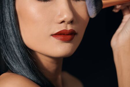 Portrait of young Asian woman applying lipstickの写真素材