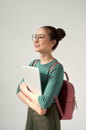 A Young Beautiful asian College Student Holding Laptop on Isolated White Backgroundの写真素材
