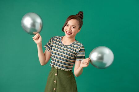 Young woman with silver balloons on green backgroundの写真素材