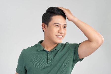 Young handsome man wearing green t-shirt over isolated background Smiling confident touching hair with hand up gesture, posing attractiveの写真素材