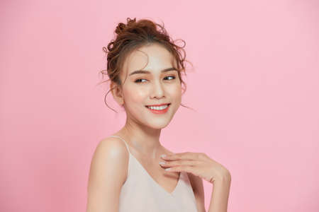 Amazed young Asian woman with clean fresh skin. Over pink background.の写真素材