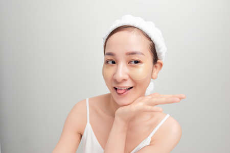 close-up of beautiful young Asian woman with bath towel on head covering her head on white background.の写真素材