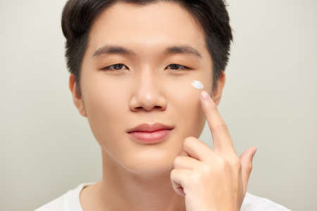 Young man with moisturizer on the faceの写真素材