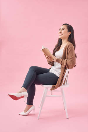 Asian female Reading Book on Chair, Full Body Isolated on pink.の写真素材