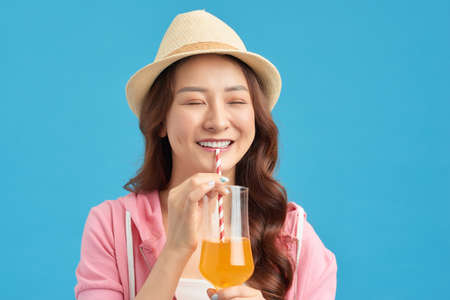 Young smiling woman holding orange juice glass. Girl with vitamin drink.