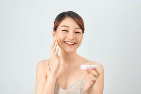 A beautiful asian woman using a natural skin care product, moisturizer or lotion. isolated with clipping pathの写真素材