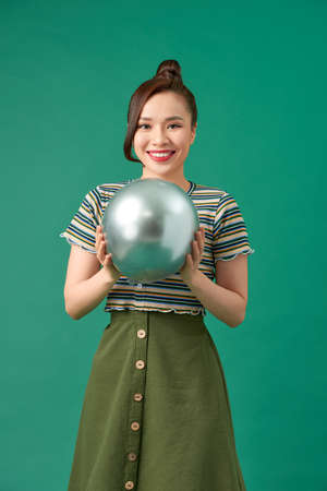 Pretty young woman in sunglasses with air balloon over green