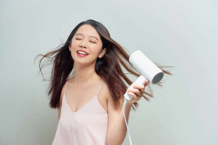 Close up portrait of beautiful young woman drying hairstyle. Cute young lady smiling .
