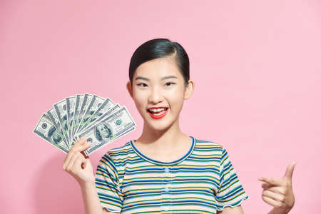 Photo of rich woman in basic clothing holding fan of dollar money isolated over pink background