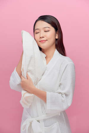 Cheerful pretty woman with healthy skin drying her face with white soft cotton towel after morning hygiene in front of cameraの写真素材