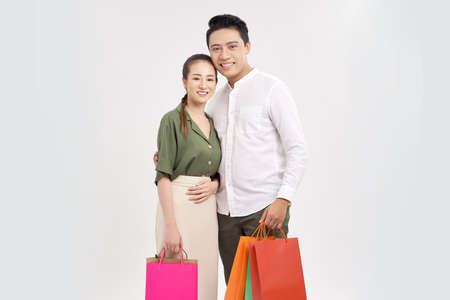 Happy couple with shopping bags, standing close to each other with smile.の写真素材