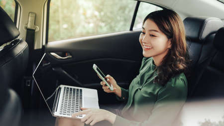 Executive businesswoman in car work on her laptop.