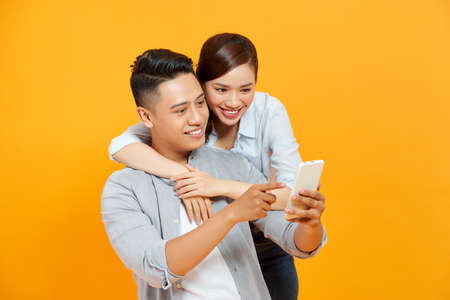 Funny couple or marriage sharing a smart phone to watch media contentの写真素材