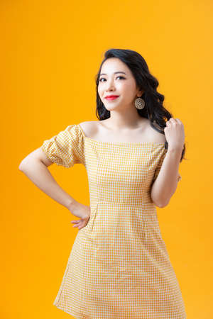 Cheerful beautiful young woman with charming smile over yellow background.