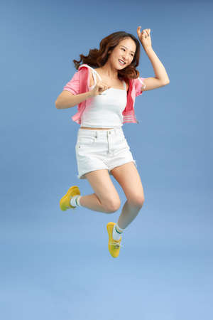 Happiness, freedom, movement and people concept - smiling young woman jumping in air.