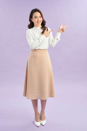 Attractive brunette girl isolated over purple background pointing at a copy spaceの写真素材