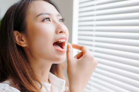 Young asian beauty young woman eating pills and drinking waterの写真素材