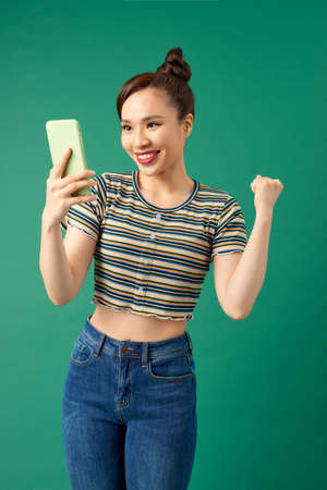 Sociable beautiful woman with asian appearance taking selfie or speaking on video call using cell...