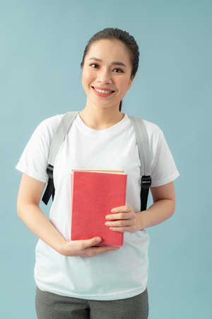 Woman with a bag and red books on her hands over blue backgroundの写真素材