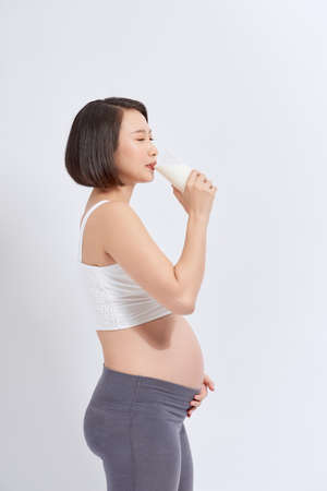 Portrait of pregnant woman with milk in glass at home.の写真素材