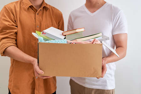 Enjoying giving back to community. Man holding donation box in his hands standing against white backgroundの写真素材