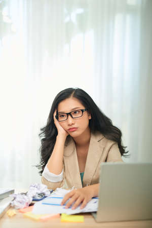 Bored young woman sit at home office table look in distance unable to work at laptop,の写真素材