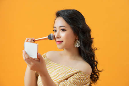 Beautiful girl with cosmetic powder brush for make up. Makeup. Make-up applying for perfect skin.の写真素材