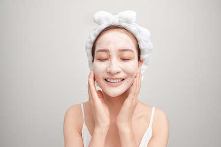 Cheerful young Asian woman with facial clay mask isolated on white background.の写真素材