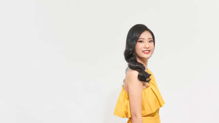Asian young woman in yellow luxury dress, posing on a white background.の写真素材