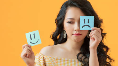 Close-up portrait of attractive girl holding in hands two different emotion stickers isolated on...