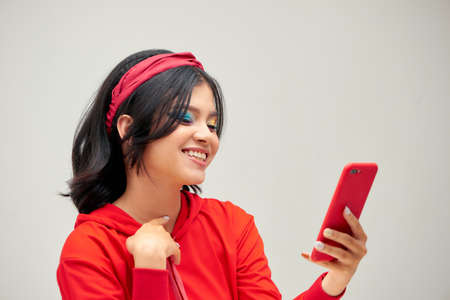 Fashion and technology. Close up studio portrait of smiling young woman using smartphone