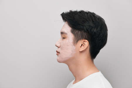 Handsome man with clay mask on his face against color backgroundの写真素材