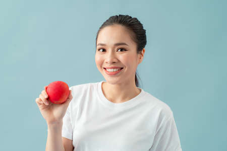 smiling woman with healthy teeth holding red apple. studio isolated portrait.の写真素材