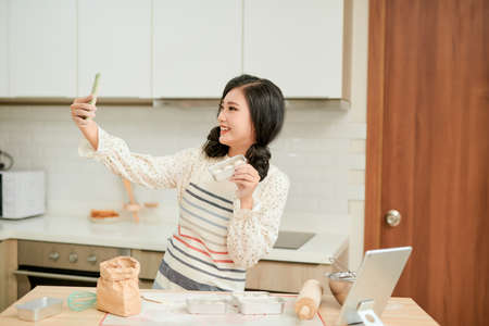 Beautiful woman make photo with fresh raw cake batter on a baking tray, womens hands painted in flour that makes the cakeの写真素材