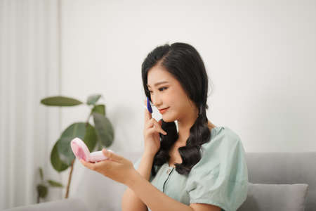 Woman applying cosmetic powder puff on her faceの写真素材
