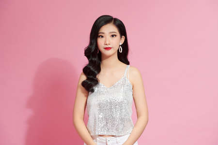 woman in elegant shiny dress on a pink background